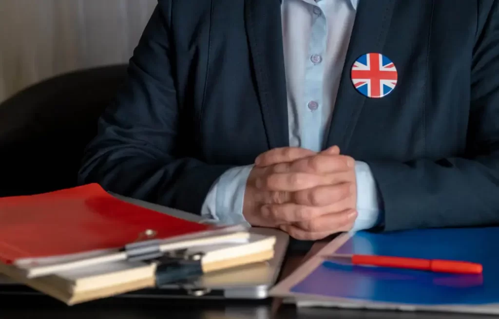 Person wearing a suit, sitting at a desk with documents and folders, related to the Minister of Religion visa for UK immigration