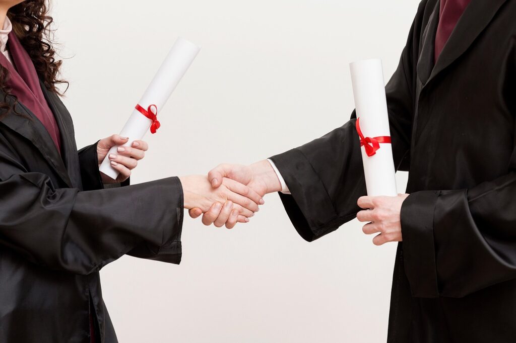 A diverse group of graduates in caps and gowns holding hands in celebration, symbolizing international students affected by the UK's new Graduate Visa changes.