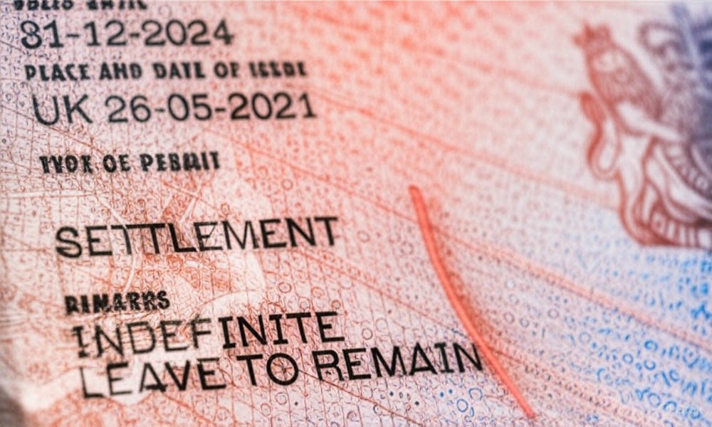 Close-up of a UK Indefinite Leave to Remain (ILR) biometric residence permit card, showing security features and holder details, representing the new 10-year residency requirement for settlement