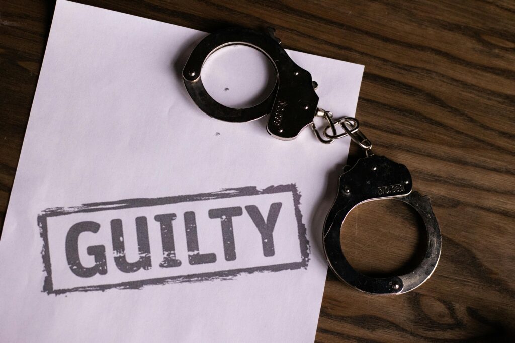 Handcuffs with the word 'Guilty' symbolising immigration crime and exploitation linked to the skilled worker visa scandal in the UK.