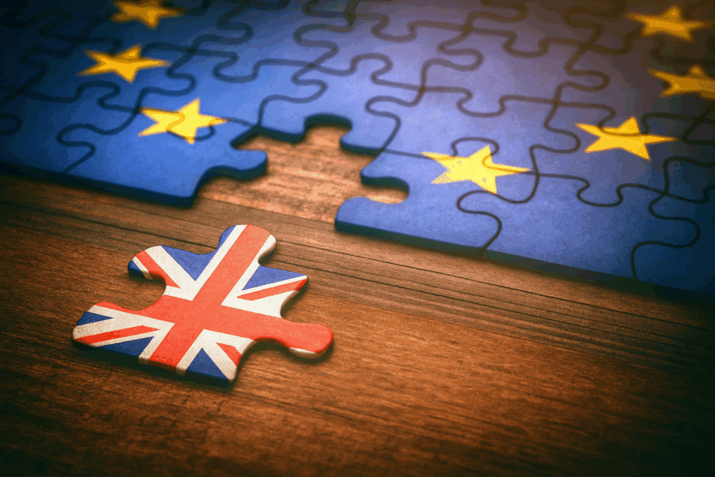 Close-up of a jigsaw puzzle with the EU flag missing a piece and a UK flag puzzle piece lying separately on a wooden table, symbolising Post-Brexit Trends in work visas and migrant workers, reflecting the shift from EU to non-EU migration, policy changes, sector impacts, and evolving visa patterns in the UK.