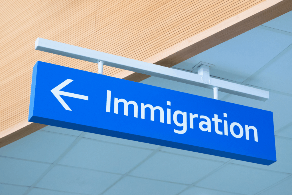 Blue airport-style sign reading “Immigration” with an arrow, symbolising UK border control and the process of long residence and settlement applications in 2025.